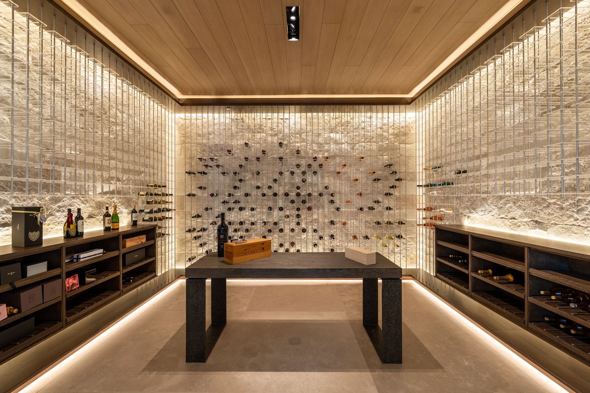 Modern custom wine cellar with a natural stone wall and floating display racks, San Diego