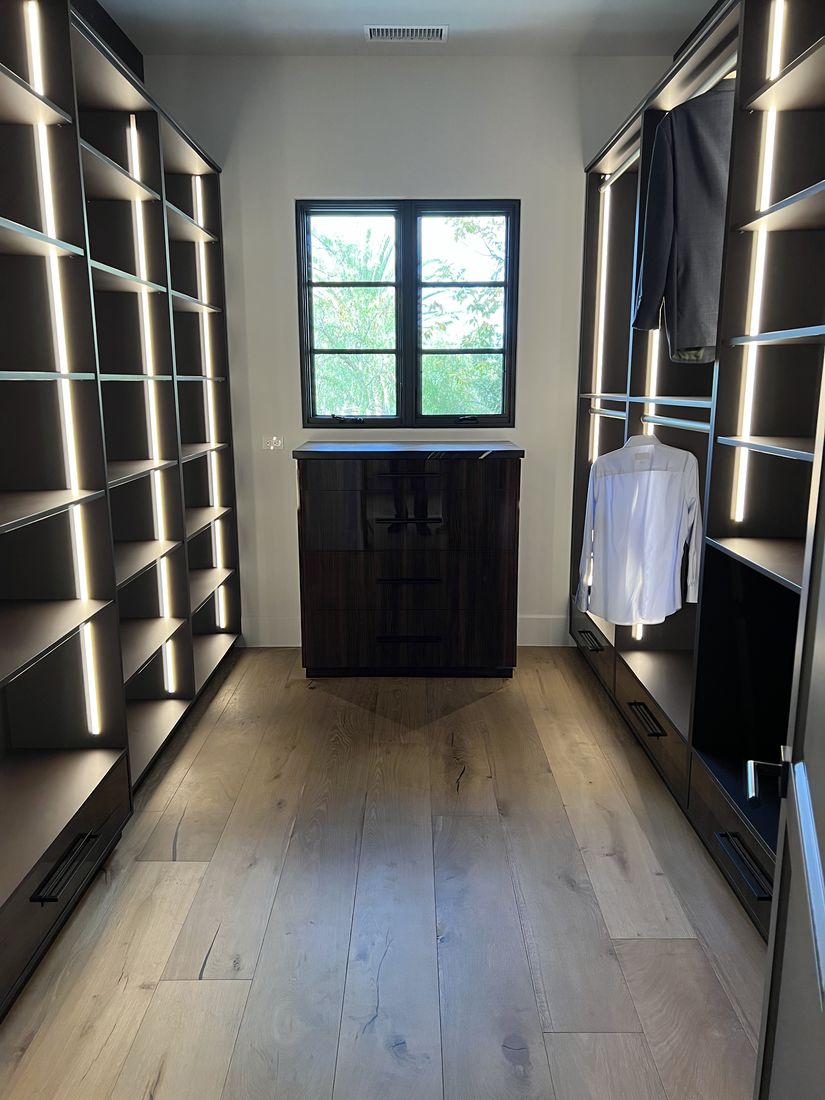 Custom walk-in closet with dark backlit shelving and a center island, San Diego
