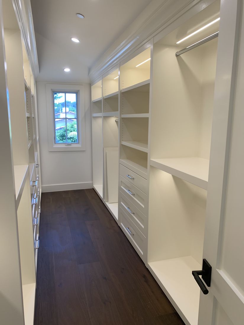 Custom walk-in closet with white built-ins and a window seat, San Diego