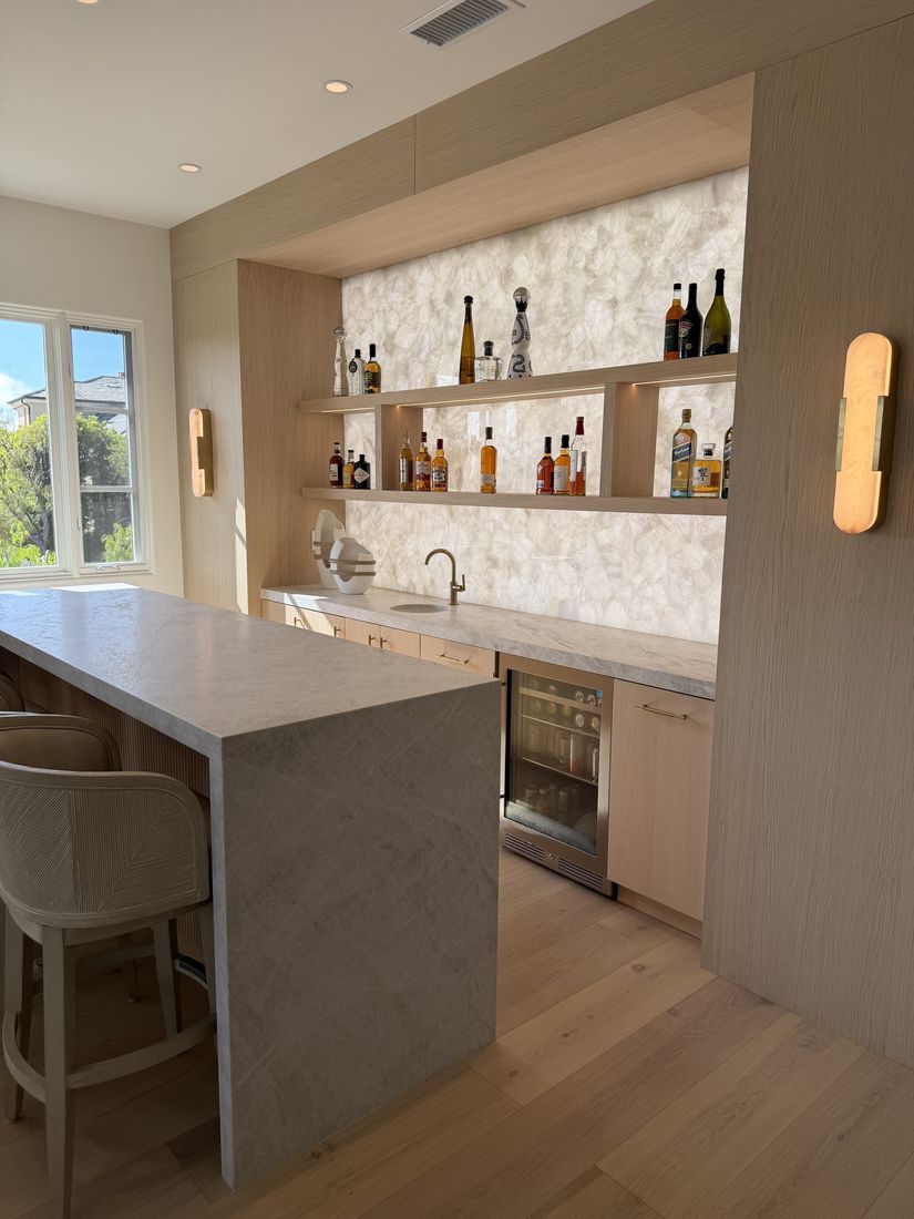 Custom wet bar with a marble waterfall island and backlit stone shelving, San Diego