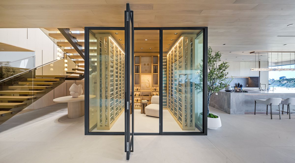 Floating glass staircase with open treads beside a glass-enclosed wine room, San Diego